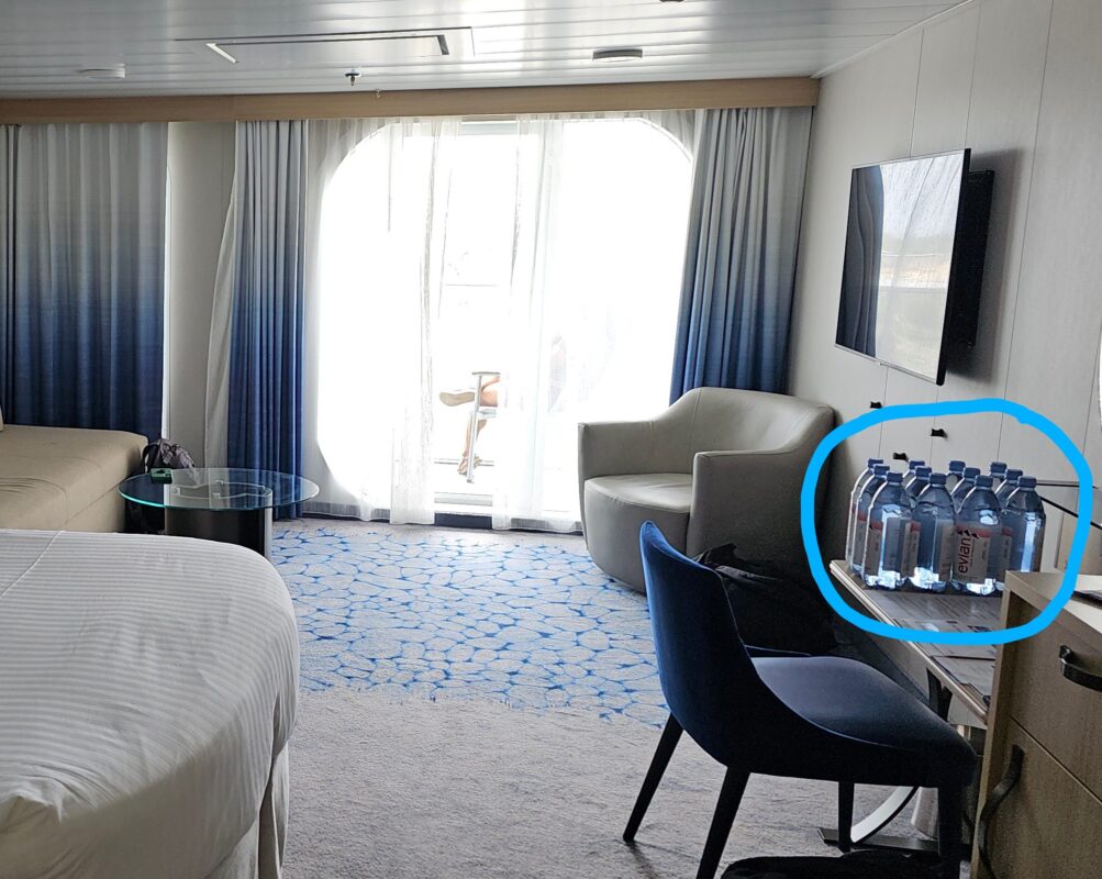 Bottled water delivery in a cruise ship suite, with nine bottles placed on the desk and highlighted for emphasis.