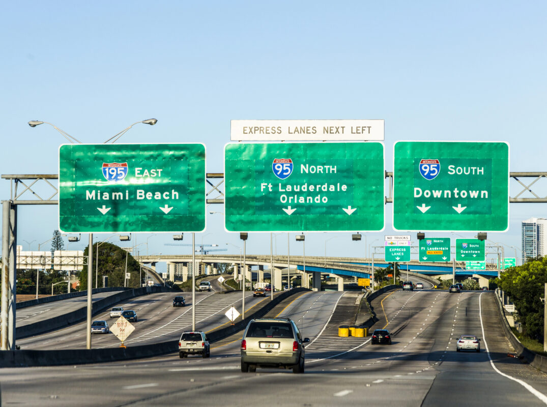 What cruise ports are on the East Coast | Green interstate highway signs in South Florida pointing toward key cruise destinations including PortMiami and Port Everglades.
