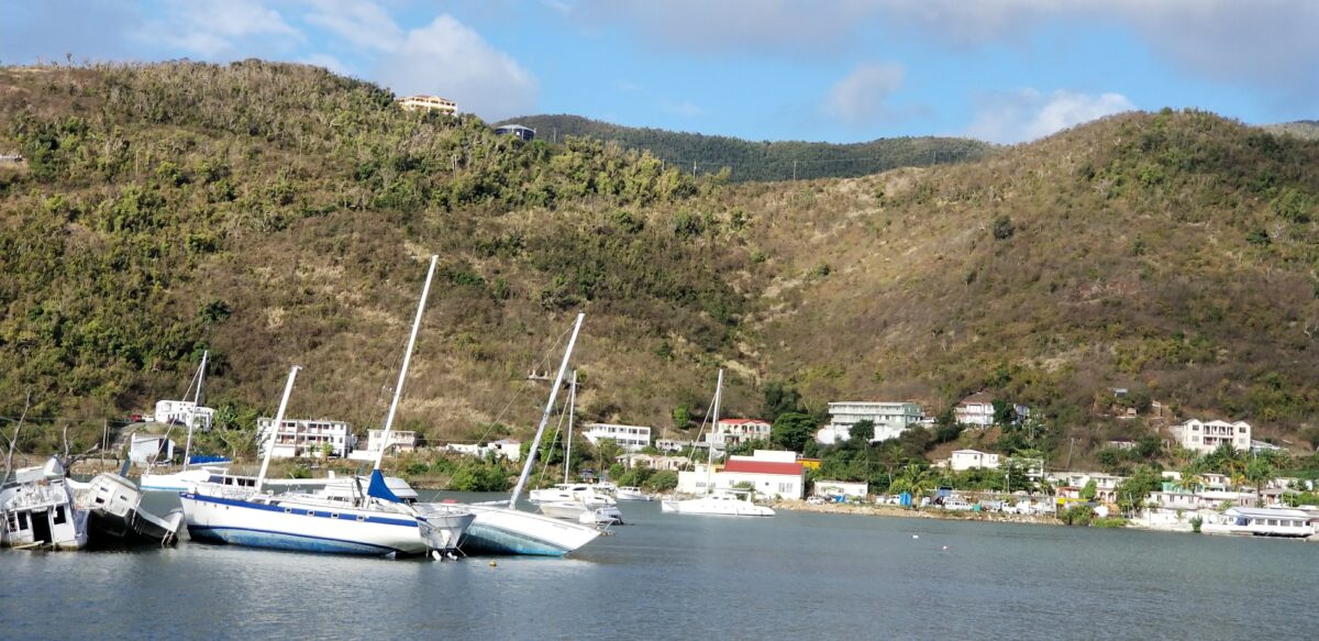 Damaged sailboats lean along the shoreline in Tortola, British Virgin Islands, a year after a hurricane.