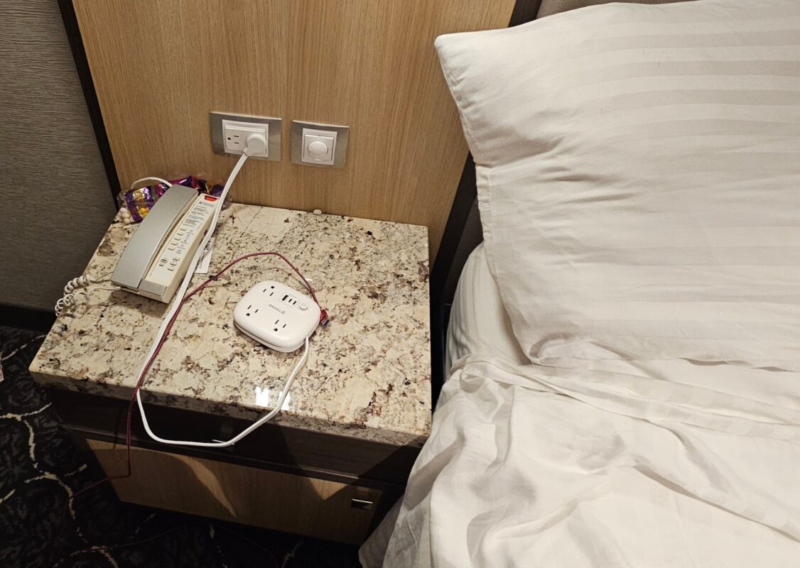 Safe cruise charging station with approved outlet extender on a granite-top nightstand.