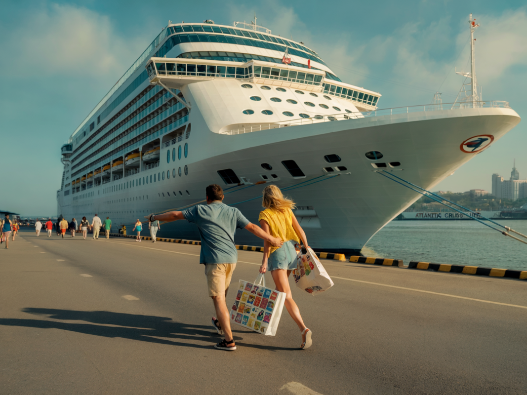 Cruise guests sprinting toward the ship docked at port, carrying shopping bags under a sunny sky.