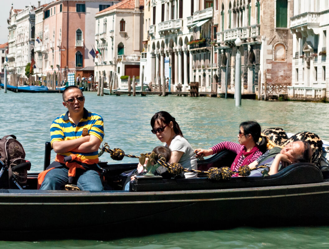 Family riding a gondola in Venice, looking tired after sightseeing during Mediterranean cruise excursions.