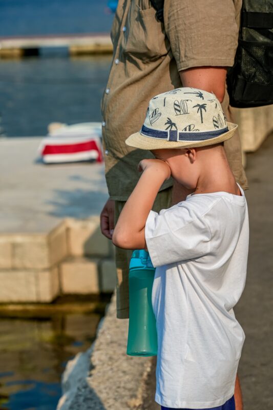 Child showing signs of fatigue on a hot day near the port, highlighting the challenge of long cruise excursions for families.