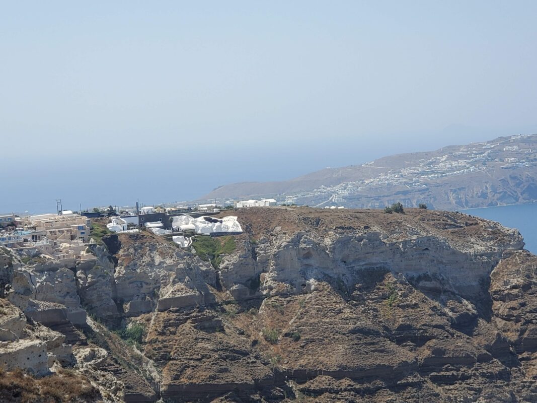 Rugged volcanic cliffs with whitewashed buildings in Santorini, Greece.