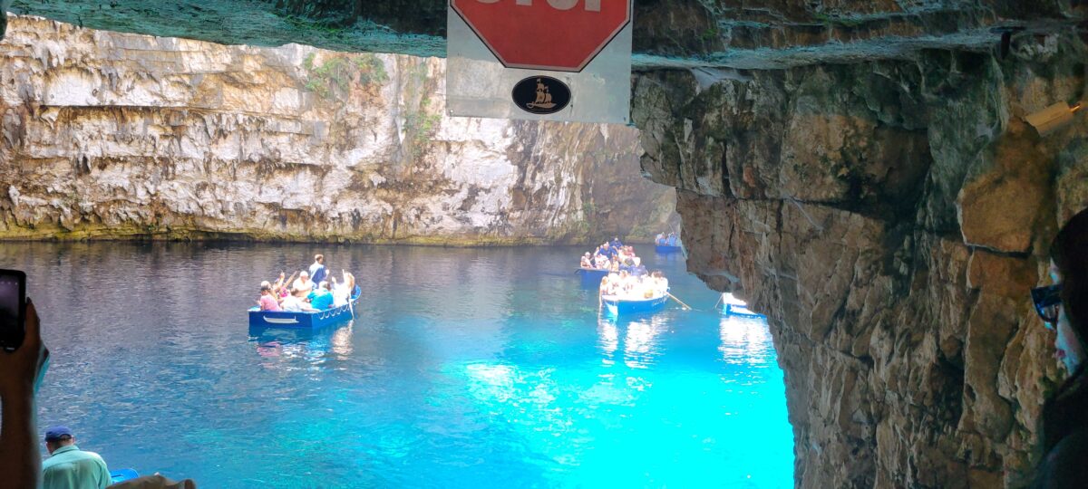 Tour boats inside Melissani Cave on Cephalonia, with bright turquoise water and rocky walls, illustrating the natural beauty of the Greek Isles.