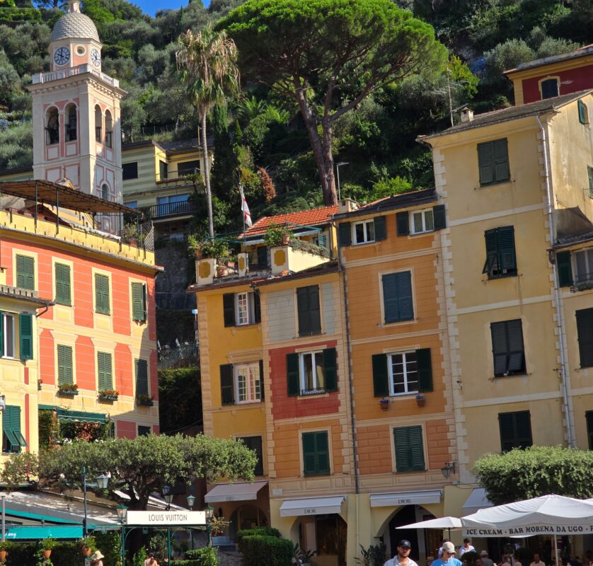 Scenic view of Portofino’s piazza with designer shops, cafés, and hillside greenery in the background.