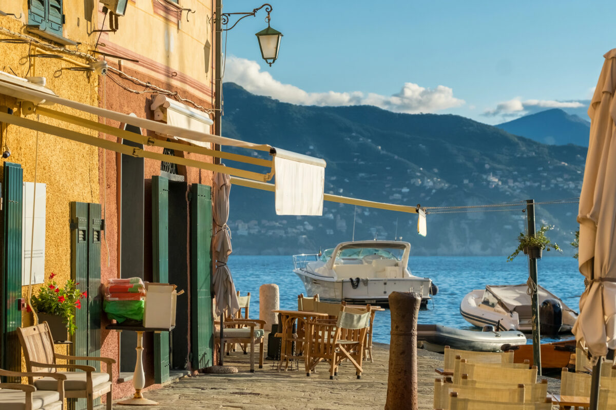 Colorful Portofino waterfront with boats tied along the harbor and mountains in the background.