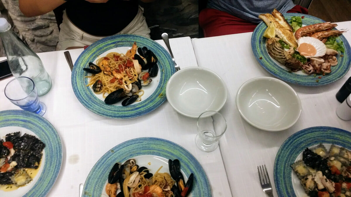 A restaurant table in Monterosso with regional Ligurian cuisine featuring pasta, mussels, and fresh fish.
