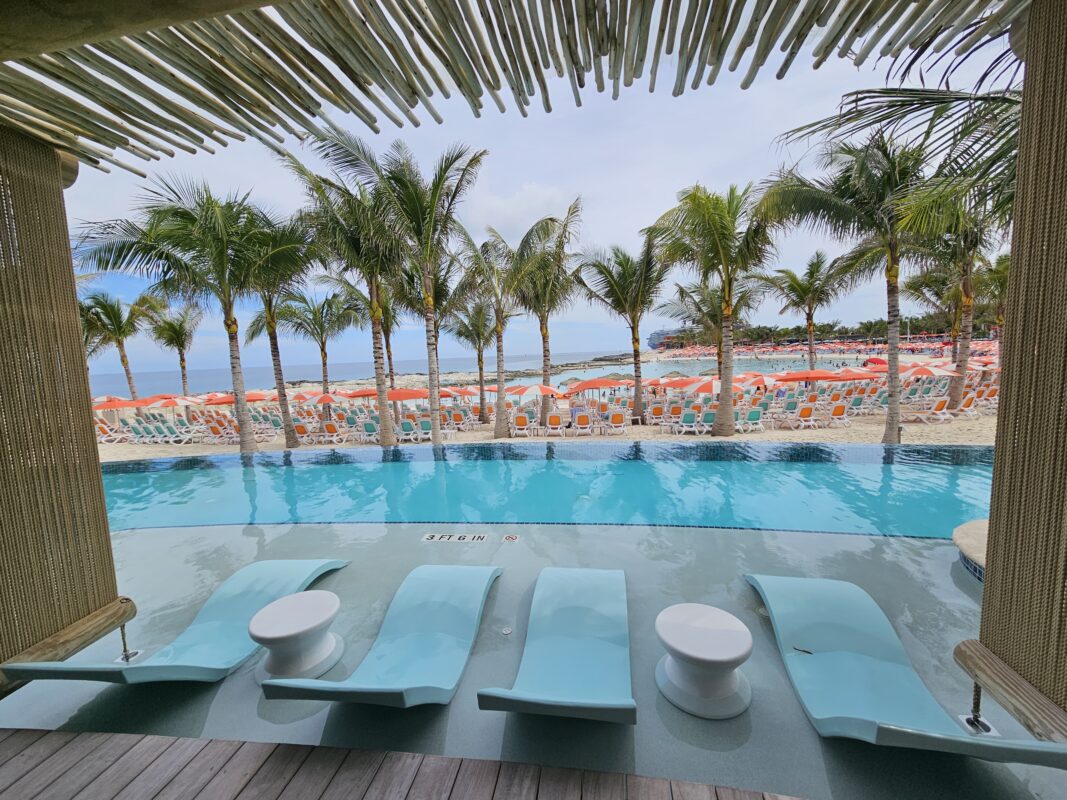 Poolside loungers facing turquoise water and palm-lined beaches at a Bahamian cruise island, showcasing the comfort of warm weather cruises.