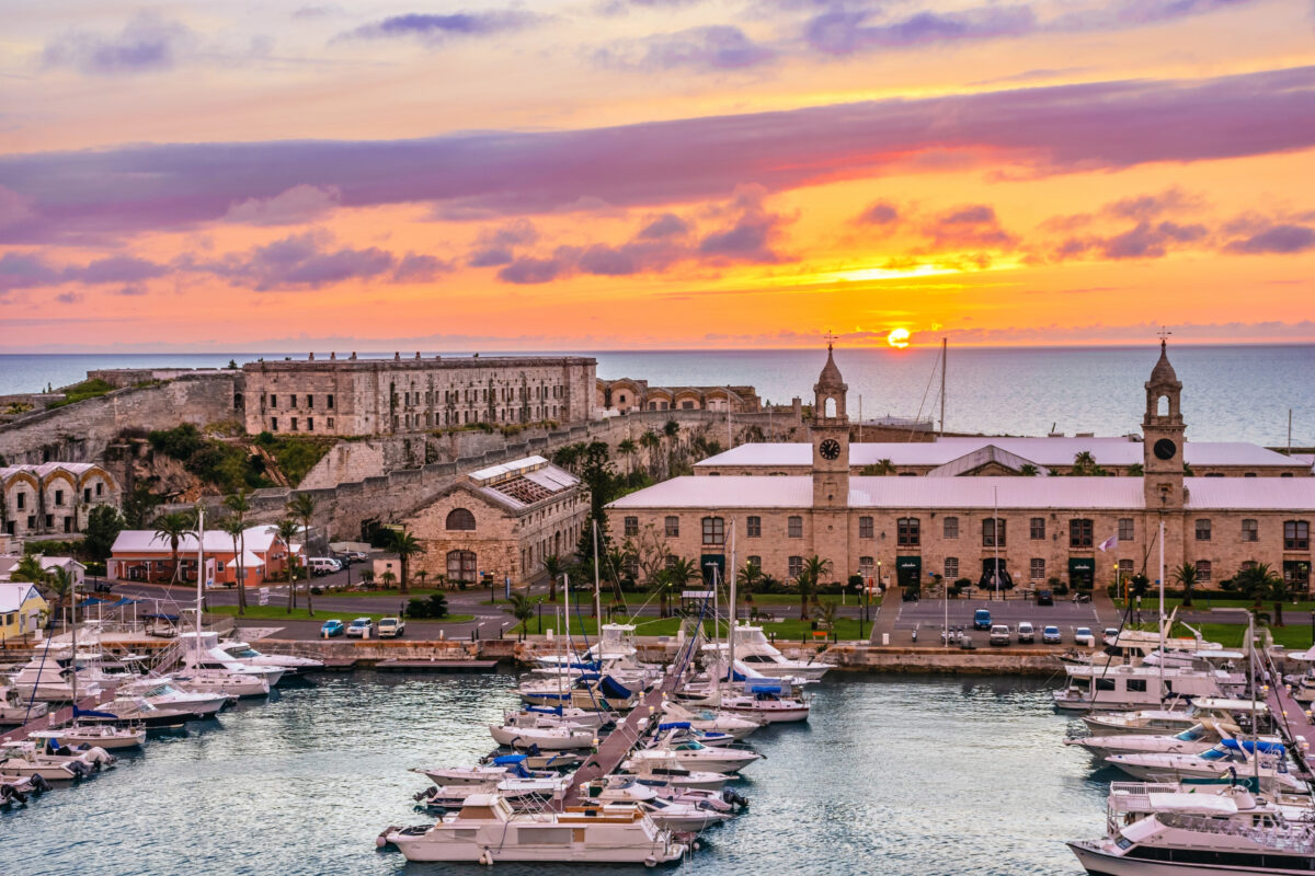 Marina filled with boats at the Royal Naval Dockyard in Bermuda with the Clocktower Mall and fortifications at sunset.