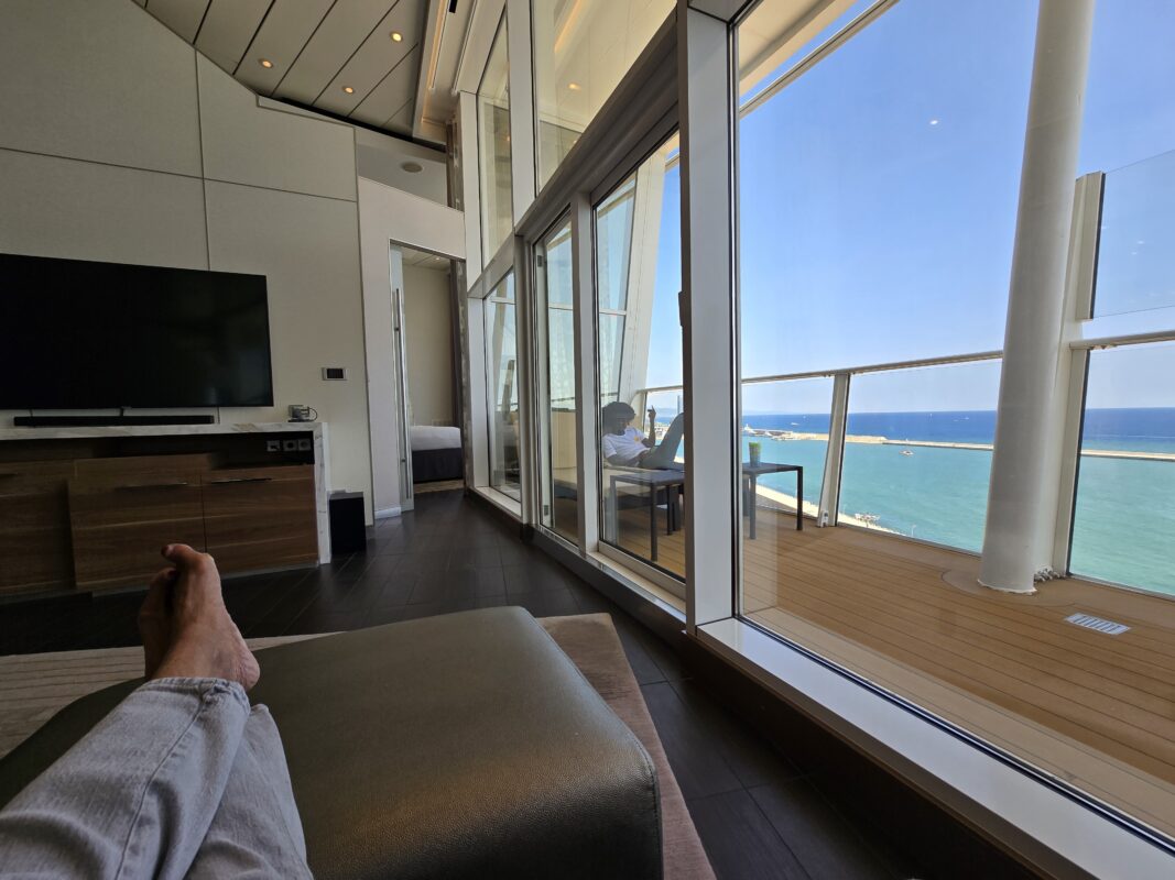 How Does RoyalUp Work | Spacious Star Class suite on Royal Caribbean with modern seating area, expansive glass walls, and private balcony overlooking the sea.