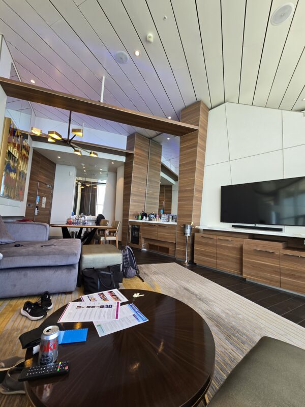 Interior of a spacious Star Class suite on Royal Caribbean showing the living area, dining table, and entertainment wall.
