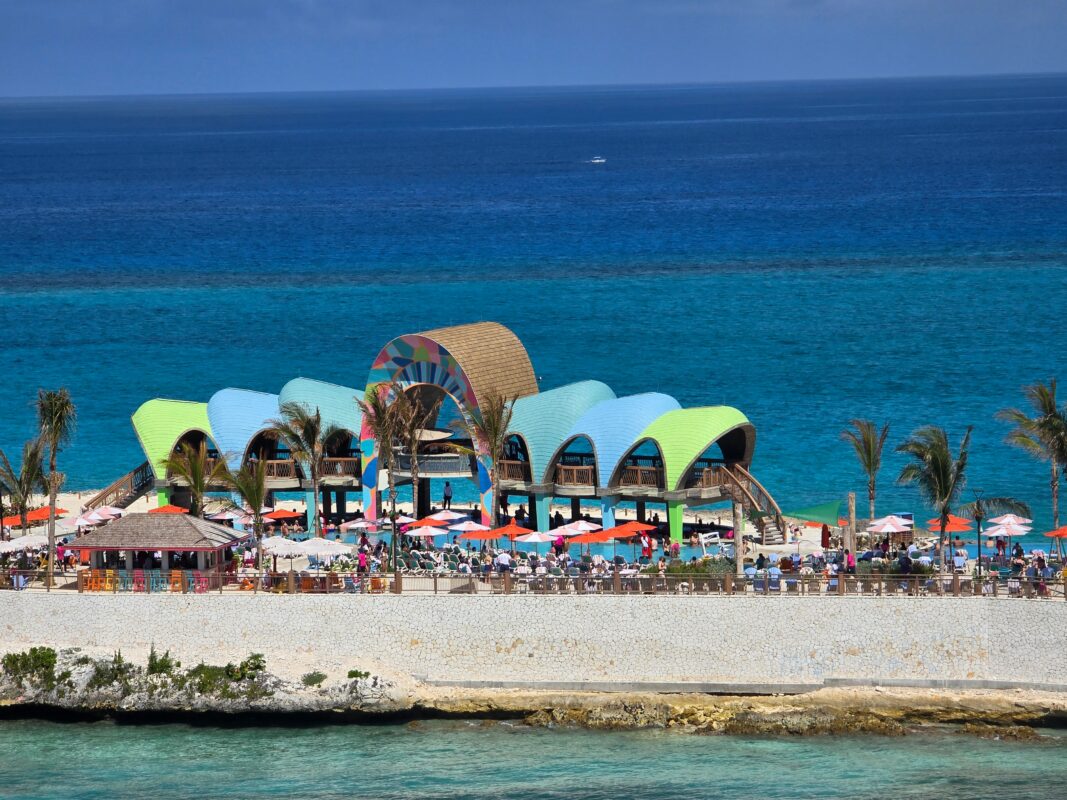 Party Cove at Royal Beach Club Paradise Island as seen from a ship, with guests gathered around the pool and beach area.