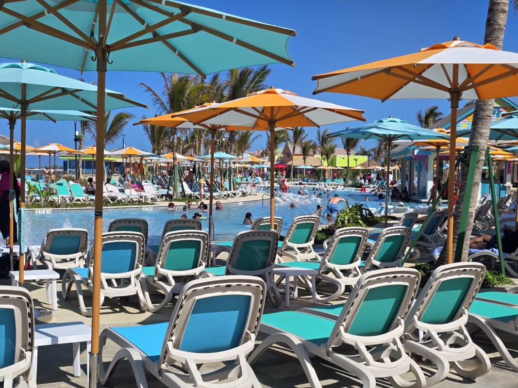 Royal Beach Club Paradise Island pool surrounded by rows of lounge chairs and shade umbrellas on a sunny day.