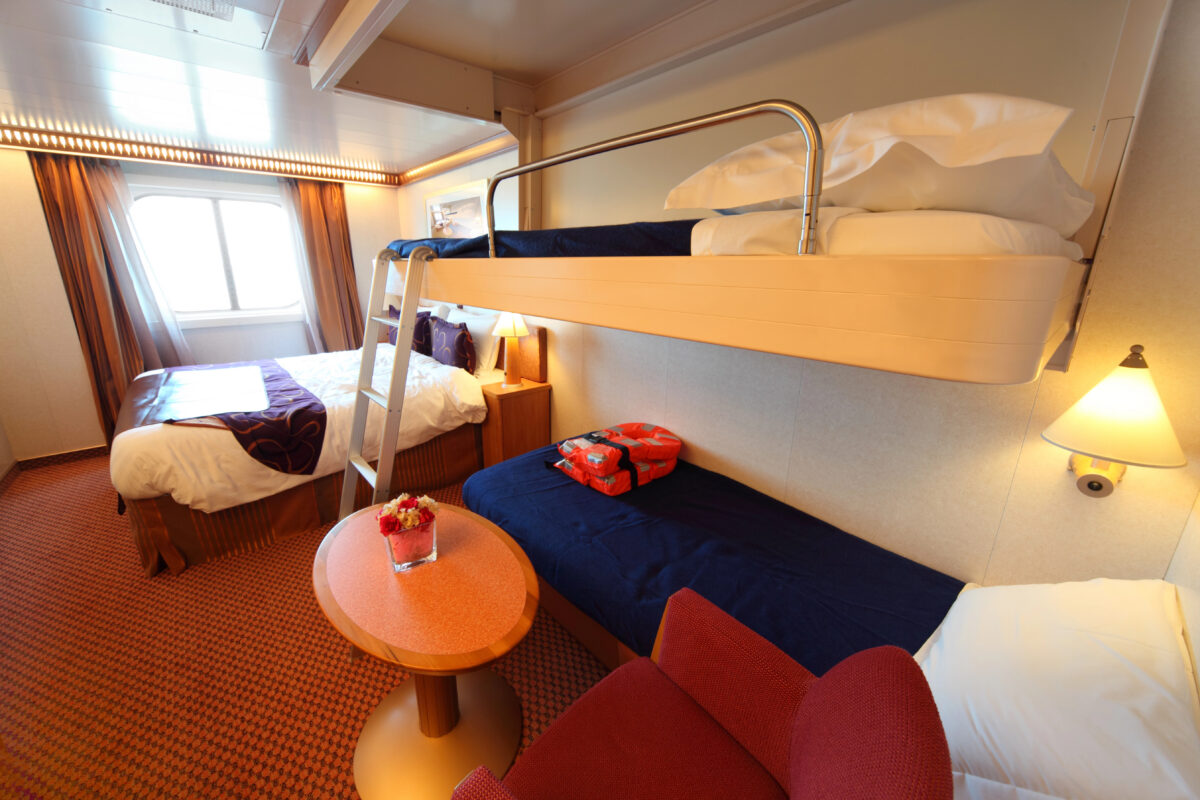 Cruise cabin with a fold-down Pullman bed extended from the wall, illustrating a common sleeping setup for 3 or 4 guests.