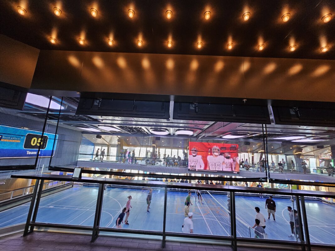 Indoor sports complex on a cruise ship with a volleyball game underway, illustrating teen friendly onboard activities.
